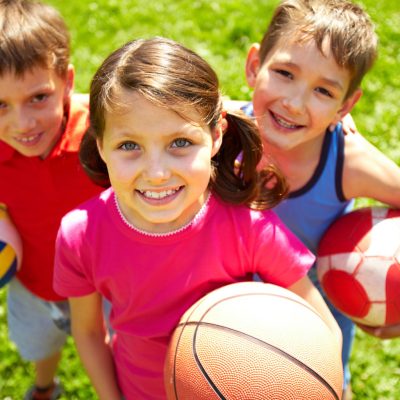 Portrait of three little children with balls looking at camera and smiling